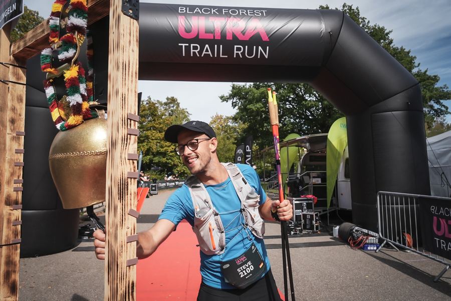 Finisher läutet die Zielglocke am Startbogen