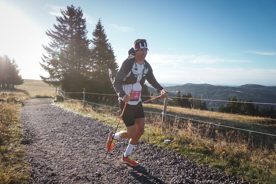 Läufer mit Stöcken auf einem Höhenweg im Morgenlicht