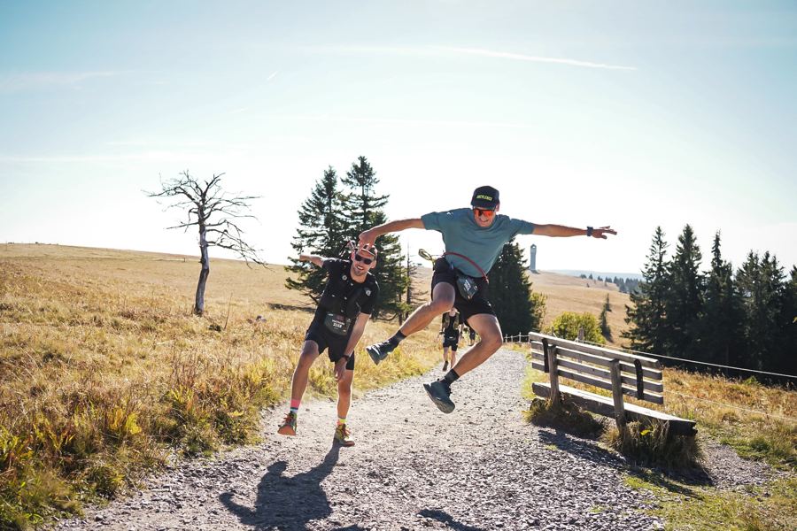 Zwei Läufer springen am Wegrand in die Luft
